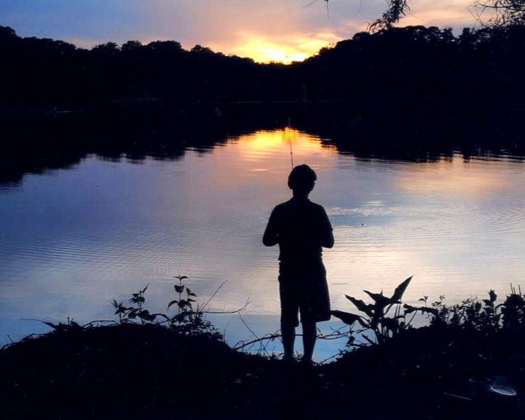 Young boy fishing during sunset