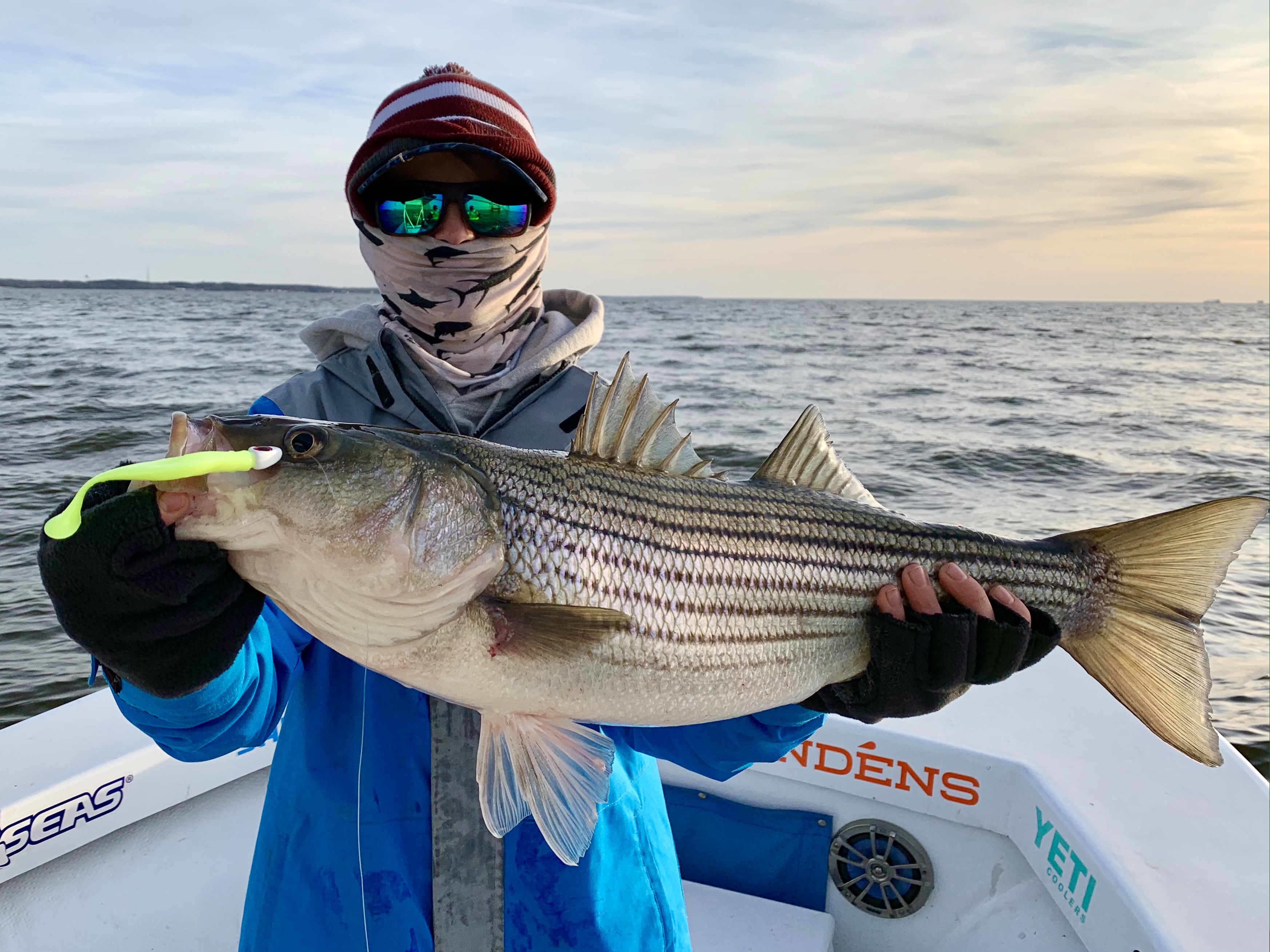Fisherman in winter gear holding a large rockfish