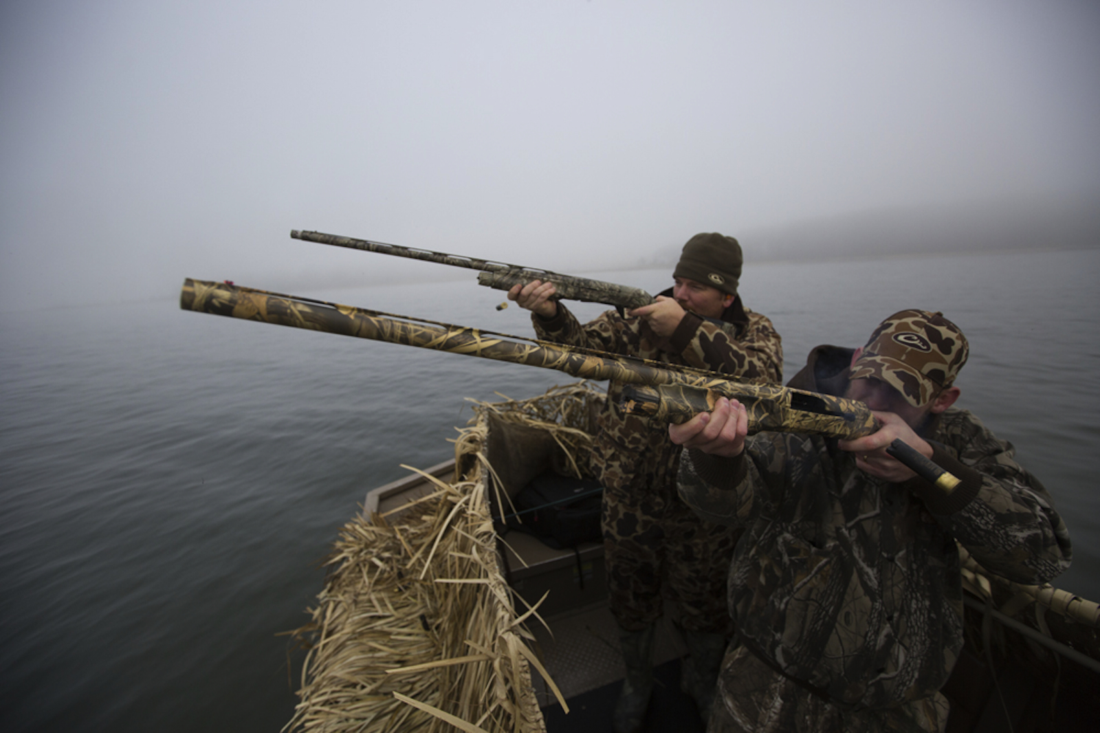 Sportsmen duck hunting from a camouflaged skiff